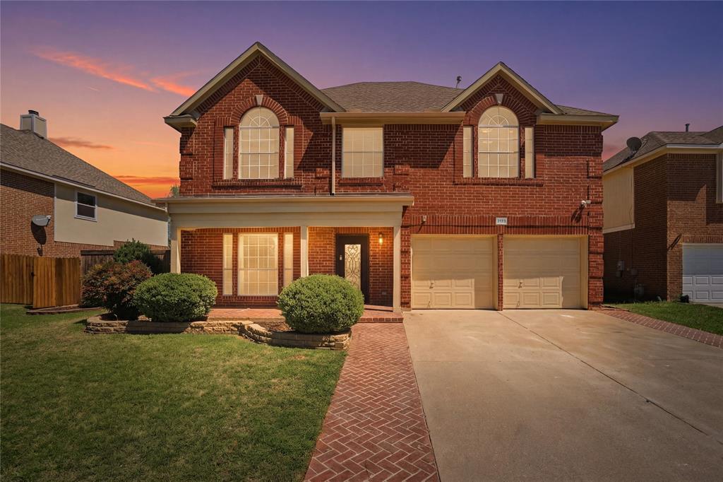 Traditional-style home with brick siding, an attached garage, driveway, and covered porch