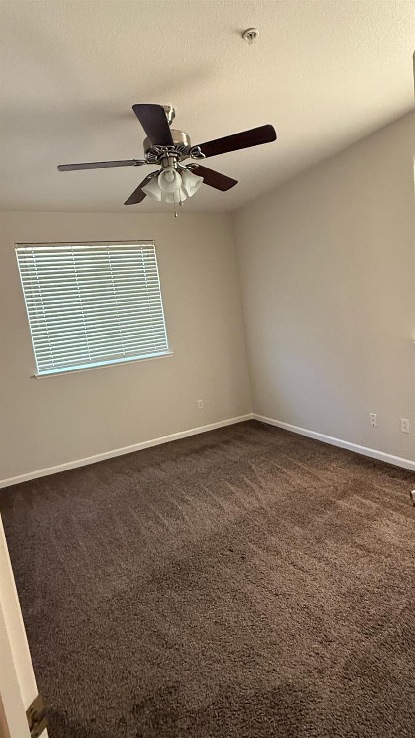 1360 Shady Lane, Unit 923 Turlock, CA 95382 - Photo 10 of 13 an empty room with a ceiling fan and a window