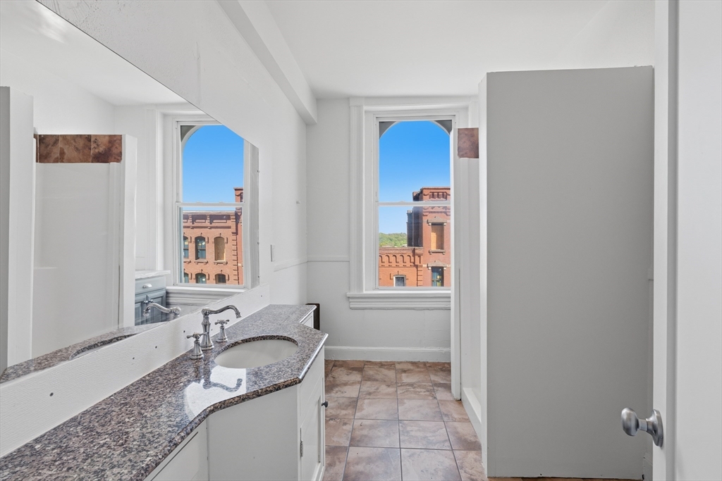 105 High Street, Unit 4P Holyoke, MA 01040 - Photo 11 of 11 a bathroom with a granite countertop sink and mirror with window