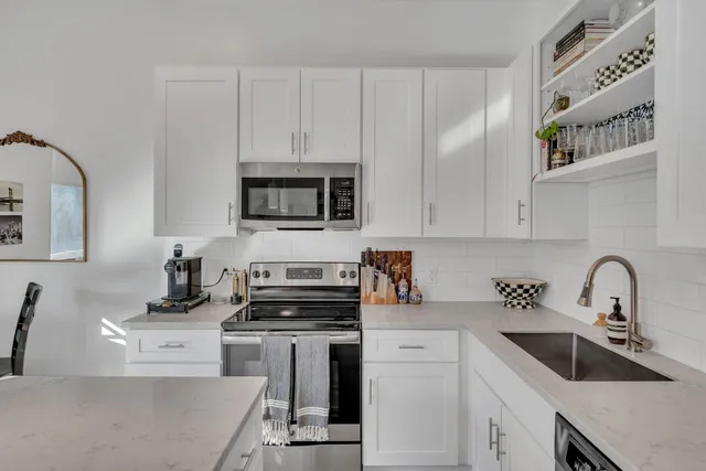 a kitchen with white cabinets a sink and appliances