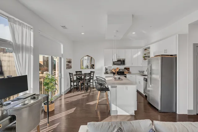 a living room with stainless steel appliances furniture and a flat screen tv