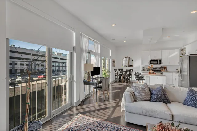 a living room with furniture kitchen view and a wooden floor