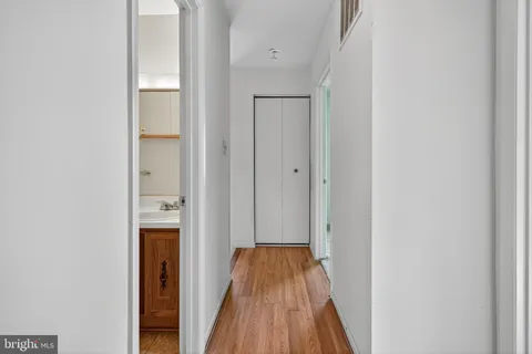 a view of a hallway with wooden floor and a bathroom