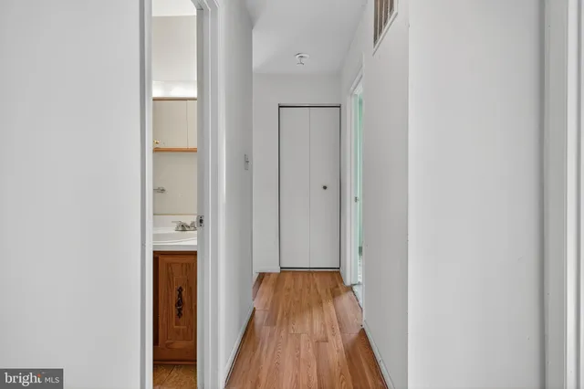 a view of a hallway with wooden floor and a bathroom