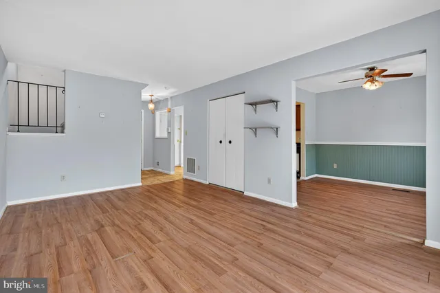 a view of empty room with wooden floor and fan