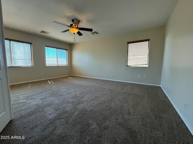 an empty room with windows and fan