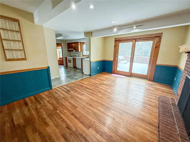 a view of an empty room with window and wooden floor