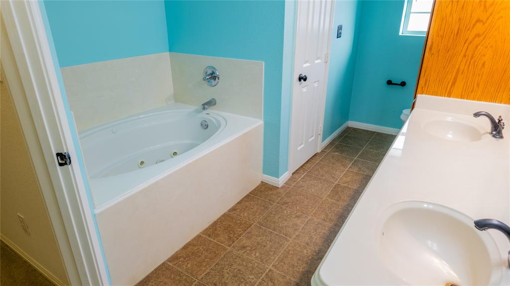 124 Topaz Circle Hewitt, TX 76643 - Photo 14 of 28 Bathroom with a jetted tub, double vanity, and dark tile patterned flooring