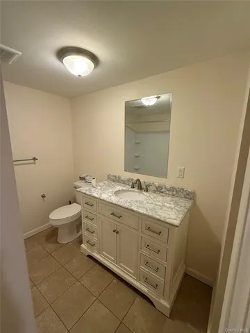 a bathroom with a granite countertop toilet a sink and a mirror