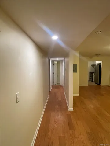 a view of a hallway with wooden floor and a bathroom
