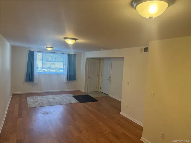 a view of an empty room with window and wooden floor
