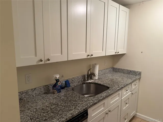 a kitchen with granite countertop a sink a stove and cabinets