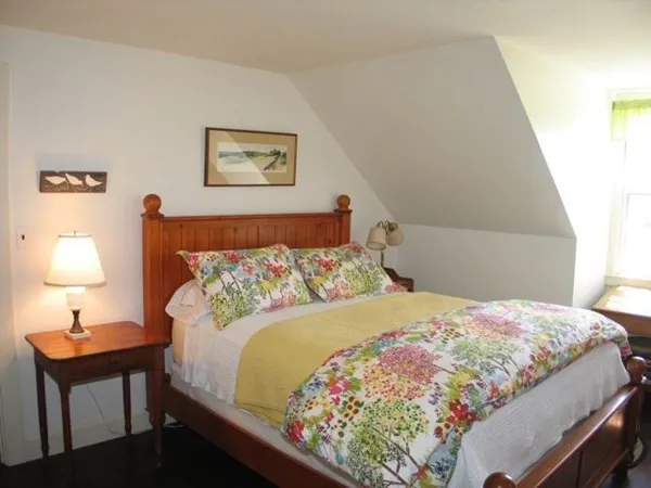 a bedroom with a bed and a lamp on dresser