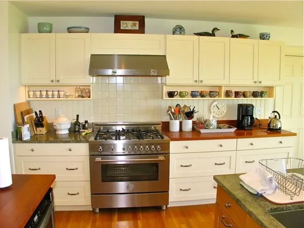 a kitchen with stainless steel appliances a stove and white cabinets