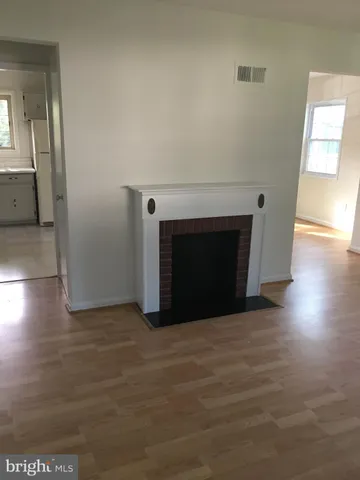a view of empty room with wooden floor and fireplace
