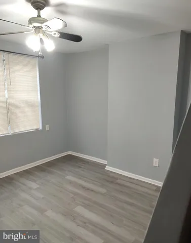 an empty room with wooden floor fan and windows