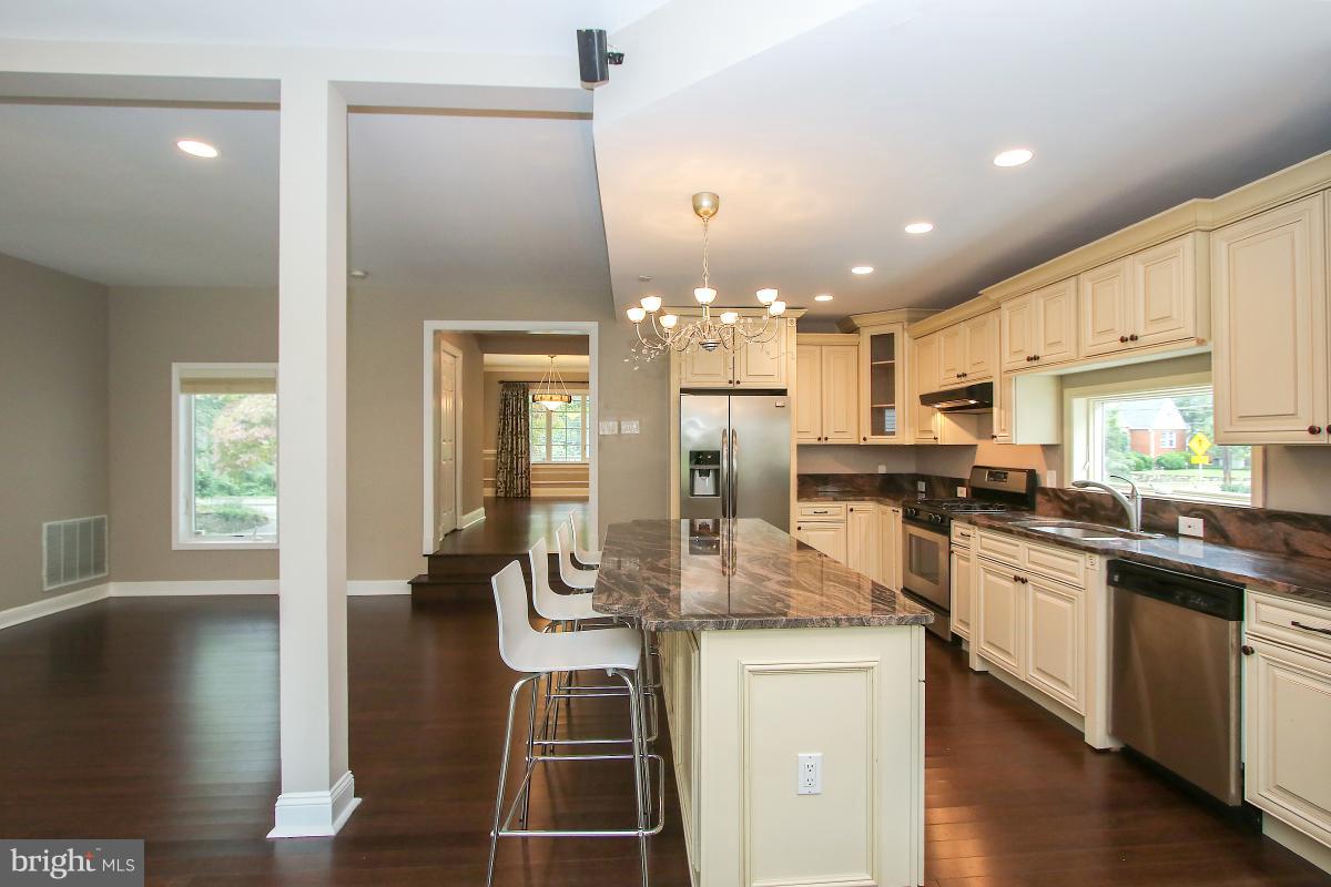 5612 Greentree Road Bethesda, MD 20817 - Photo 11 of 28 a kitchen with stainless steel appliances kitchen island granite countertop a refrigerator a stove and white cabinets with wooden floor