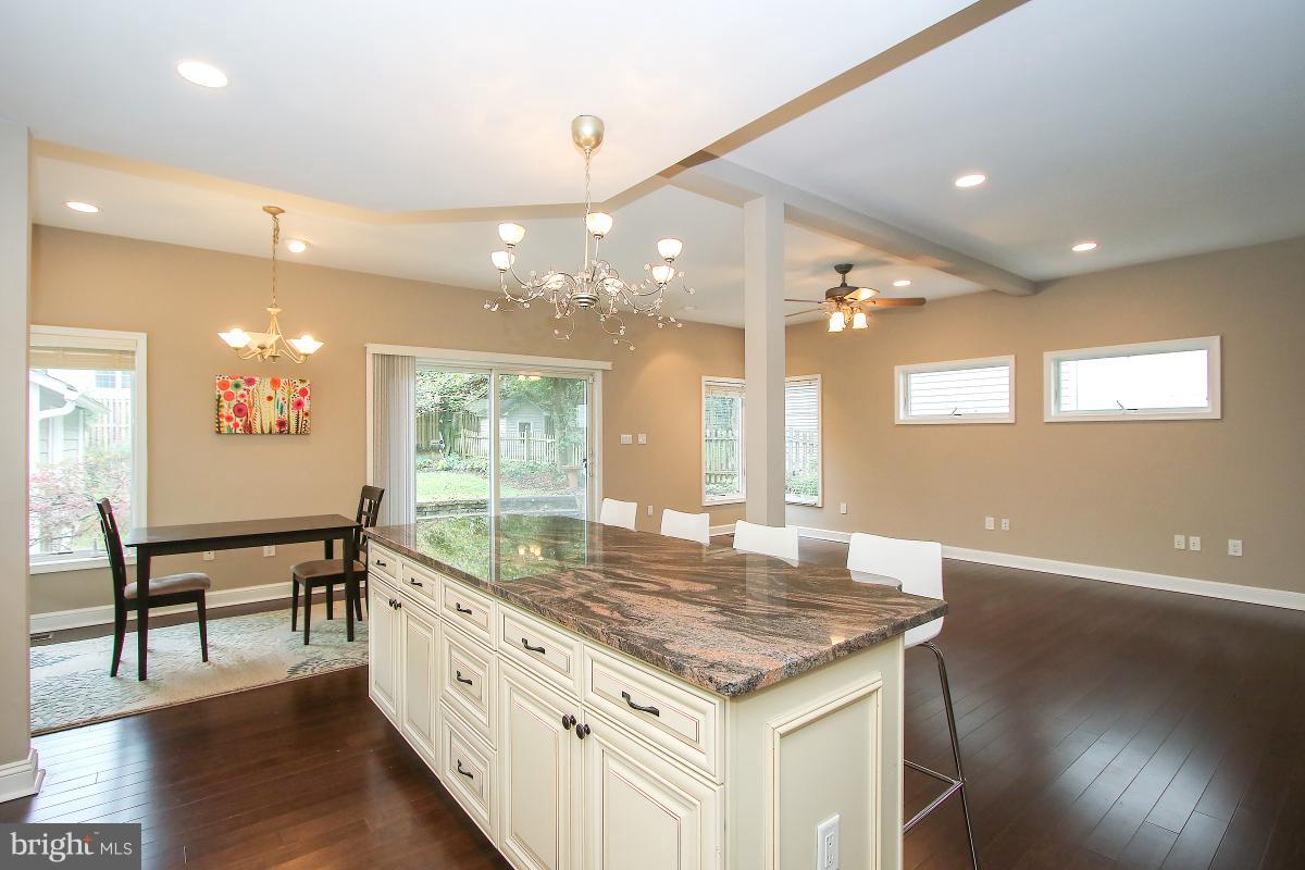 5612 Greentree Road Bethesda, MD 20817 - Photo 12 of 28 a large kitchen with kitchen island a stove a sink a dining table and chairs with wooden floor