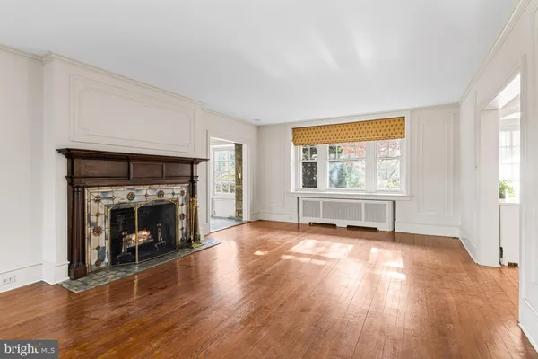 an empty room with wooden floor fireplace and windows