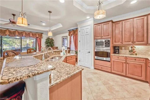 a kitchen with stainless steel appliances granite countertop a stove top oven a sink a counter space and living room view