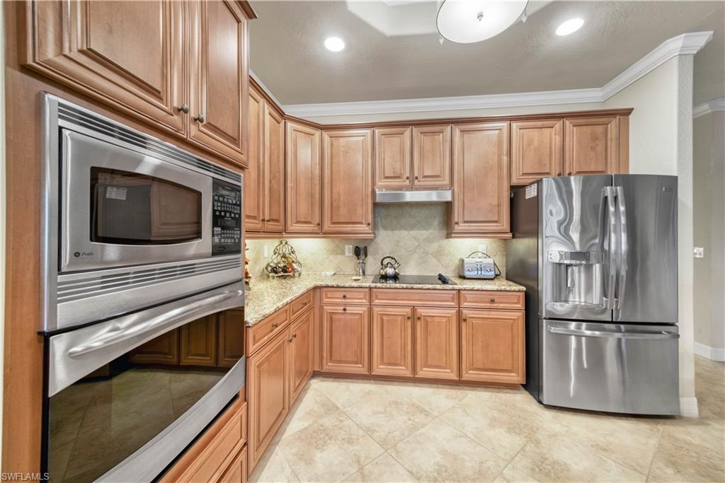 9446 Piacere Way Naples, FL 34113 - Photo 6 of 23 a kitchen with granite countertop a refrigerator stove and microwave