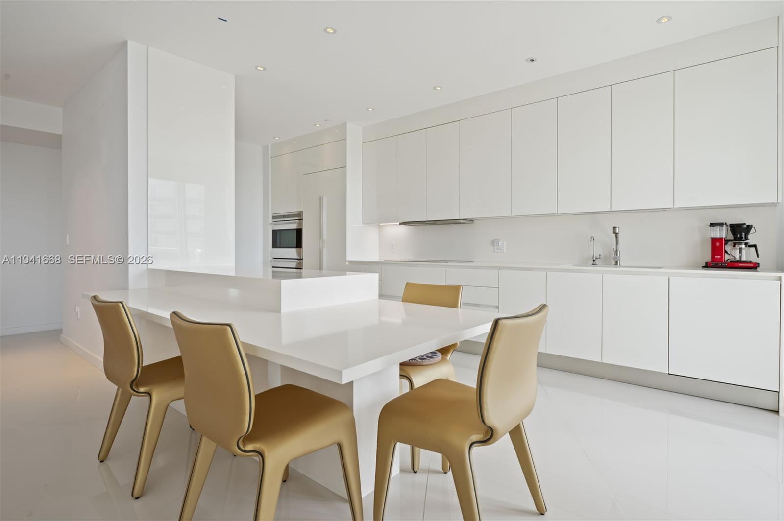 9601 Collins Avenue, Unit 908 Bal Harbour, FL 33154 - Photo 9 of 29 a kitchen with a dining table chairs and white cabinets