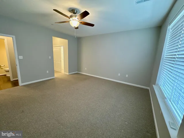 an empty room with a window and a ceiling fan