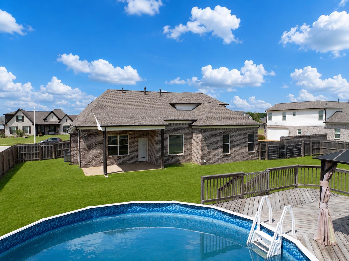 70 Trinity Cove Atoka, TN 38004 - Photo 17 of 19 Brick exterior residence with a covered patio, an expansive lawn, a multi-level wood deck, and an above-ground pool