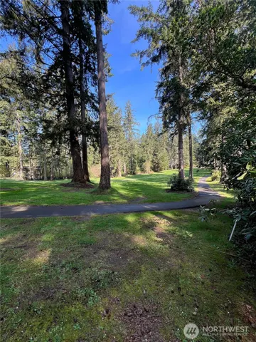 a view of grassy field with benches and trees all around
