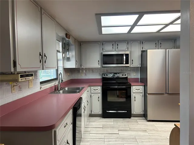 a kitchen with granite countertop a refrigerator stove top oven and sink