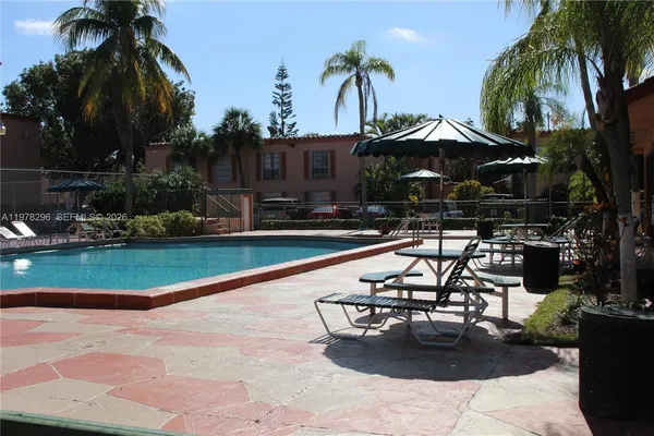 a swimming pool with outdoor seating yard and palm trees