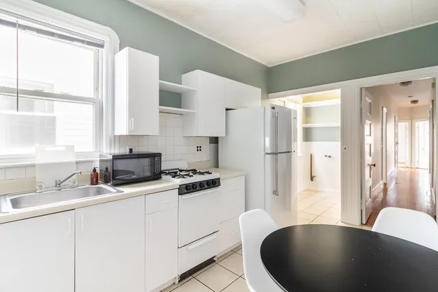 a kitchen with a sink a refrigerator and white cabinets