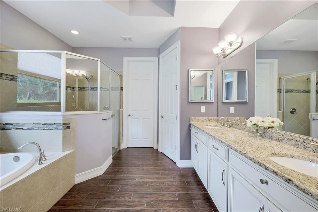 14374 Tuscany Pointe Trail Naples, FL 34120 - Photo 12 of 22 a bathroom with a granite countertop double vanity sink a mirror and a bathtub