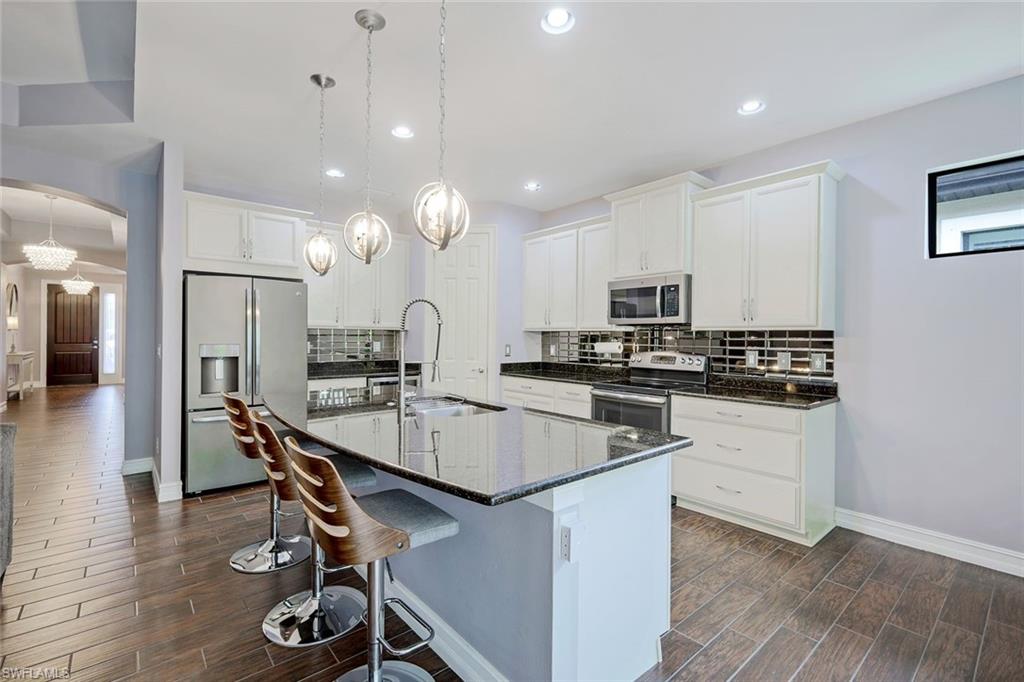 14374 Tuscany Pointe Trail Naples, FL 34120 - Photo 7 of 22 a kitchen with kitchen island granite countertop a sink a counter space stainless steel appliances and cabinets