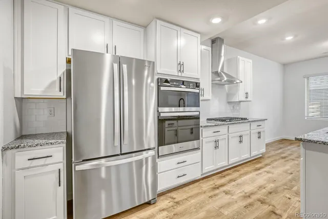 a kitchen with stainless steel appliances white cabinets and a refrigerator