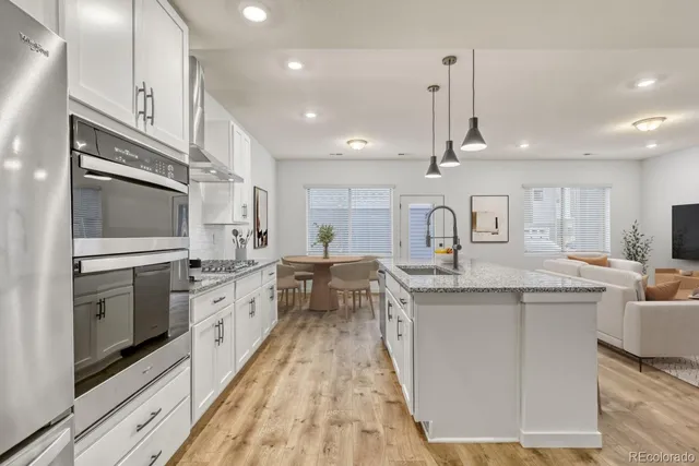 a kitchen with stainless steel appliances granite countertop a stove and white cabinets with wooden floor