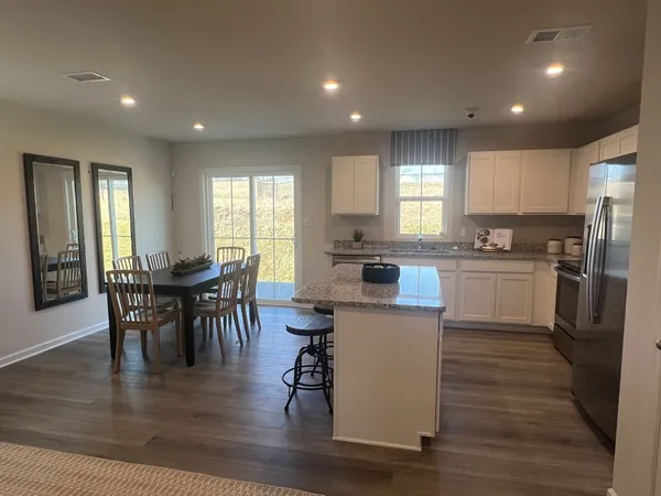a kitchen with a table chairs refrigerator microwave and cabinets
