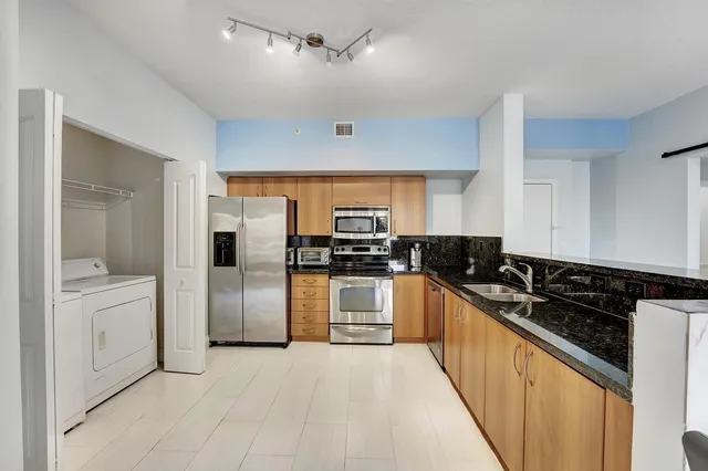 a kitchen with granite countertop a sink stainless steel appliances and white cabinets