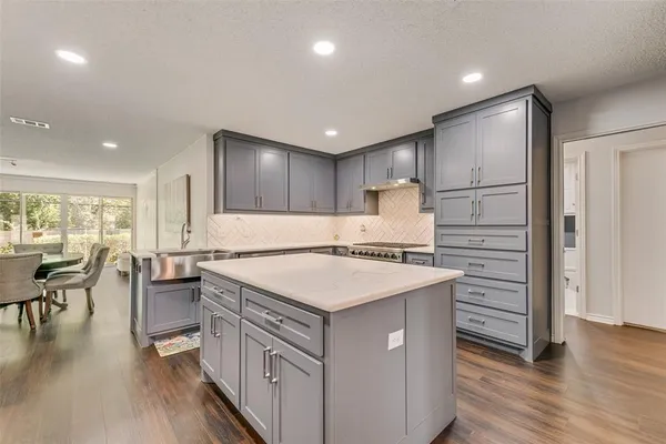 a kitchen with a stove a refrigerator a dining table and chairs with wooden floor