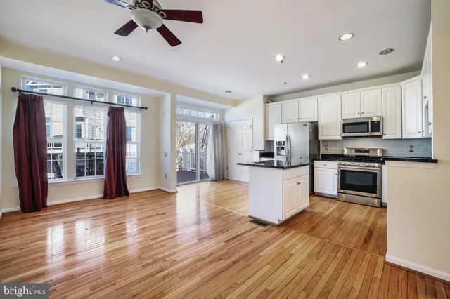 a kitchen with kitchen island wooden floors appliances and cabinets