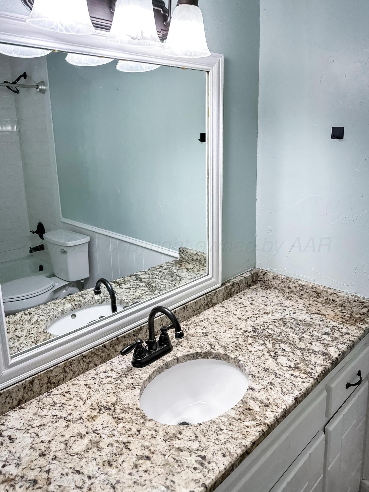 216 Skycrest Street Borger, TX 79007 - Photo 16 of 20 a bathroom with a granite countertop sink and a mirror