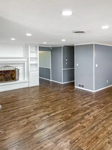 an empty room with wooden floor and fireplace