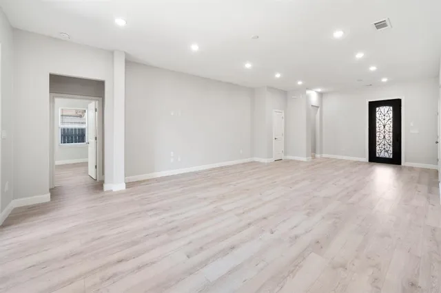 a view of an empty room with wooden floor and closet