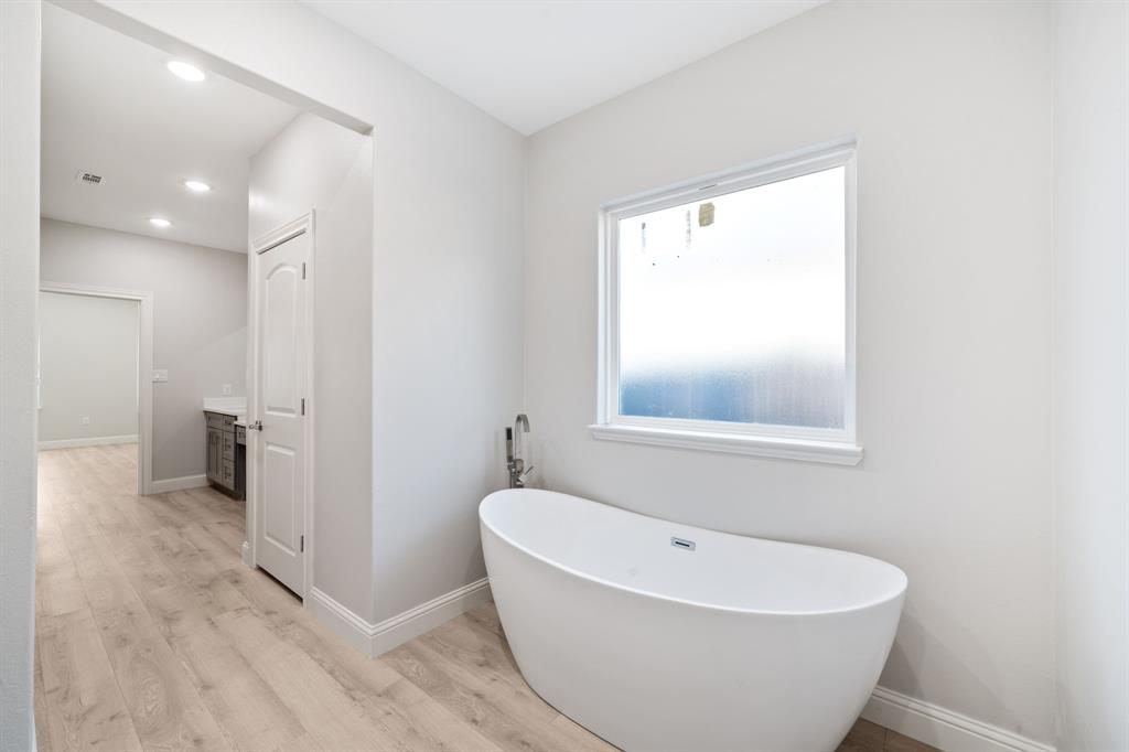 8809 Isom Lane Dallas, TX 75249 - Photo 23 of 40 a white bath tub sitting in a bathroom