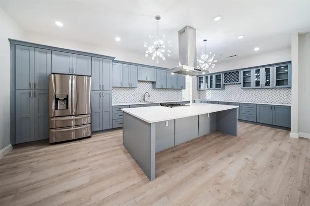 a kitchen with kitchen island a sink stainless steel appliances and wooden floor