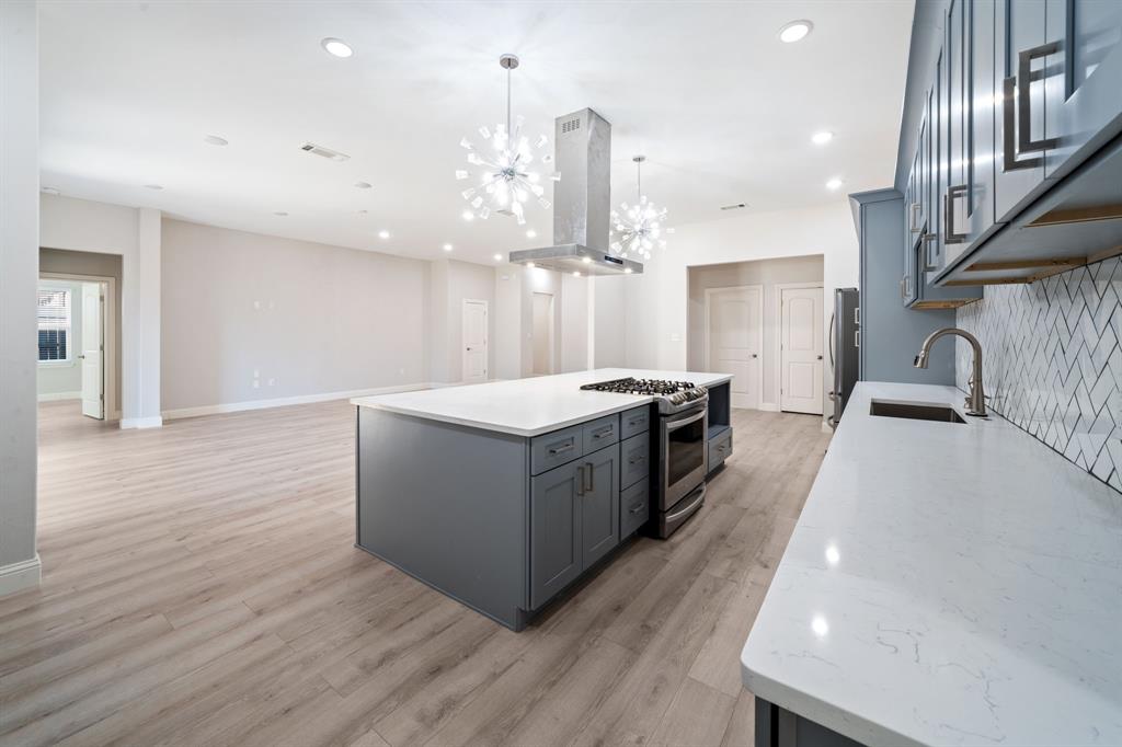 8809 Isom Lane Dallas, TX 75249 - Photo 6 of 40 a large kitchen with stainless steel appliances kitchen island granite countertop a large counter top and wooden floors