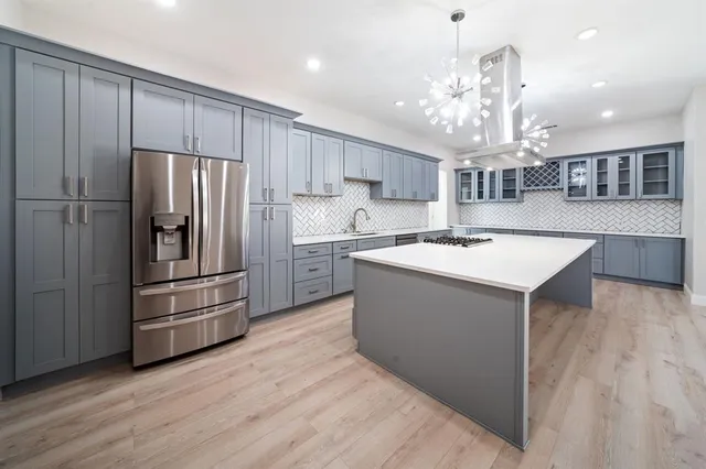 a kitchen with stainless steel appliances granite countertop a refrigerator a sink dishwasher a stove and a dining table with wooden floor