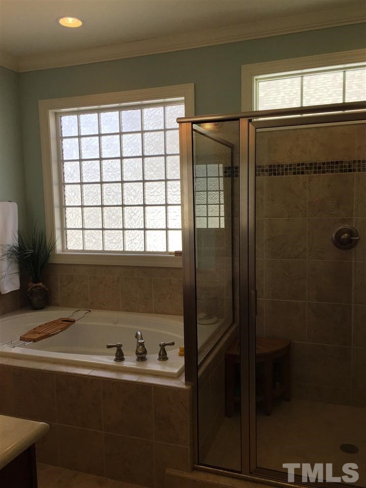 1307 Ileagnes Road Raleigh, NC 27603 - Photo 18 of 24 Spa like bath features a deep jetted tub and a large tiled shower. Window over tub and transom window in shower fill the bathroom with natural light.