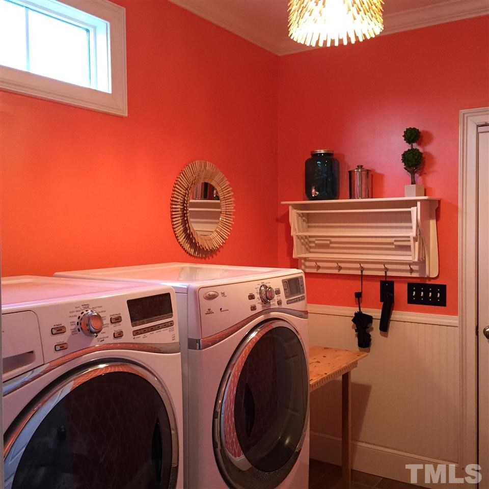 1307 Ileagnes Road Raleigh, NC 27603 - Photo 23 of 24 The main floor laundry room has direct access to the two car garage. It features a transom window, tile floor, bead board wainscoting and a unique clothespin light fixture. This room might make doing laundry fun!