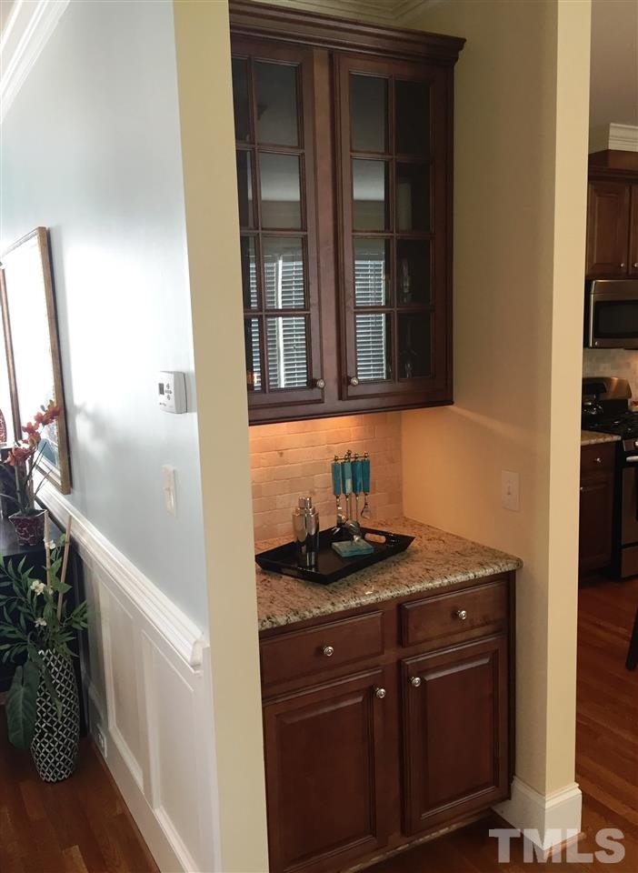 1307 Ileagnes Road Raleigh, NC 27603 - Photo 10 of 24 A great bar area or coffee station. Upper cabinets feature glass front doors and under cabinet lighting. Granite counter top and tiled backsplash.